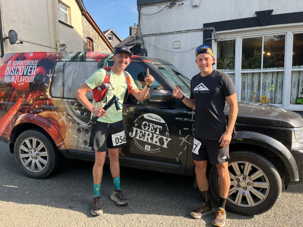 Two runners posed in front of commercial car